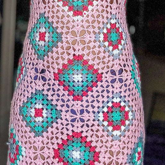 Woman wearing a colorful crochet dress with geometric patterns.